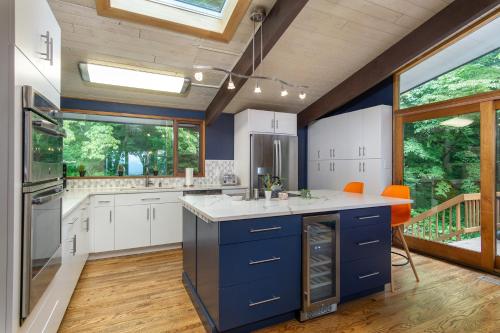 a kitchen with blue and white cabinets and windows at Retro Metro Deck House MCM Gem with Hot Tub & Spectacular Views! in Fairview