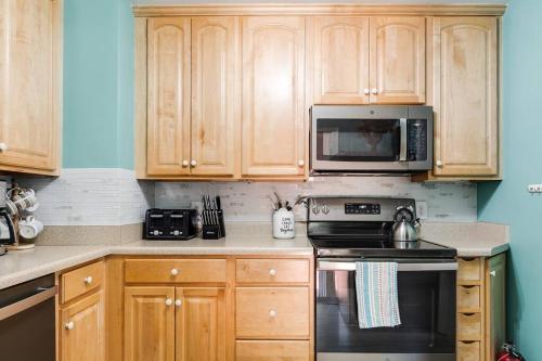 a kitchen with wooden cabinets and a stove and microwave at LG Central location FREE parking fenced yard FIRE-PIT in Richmond
