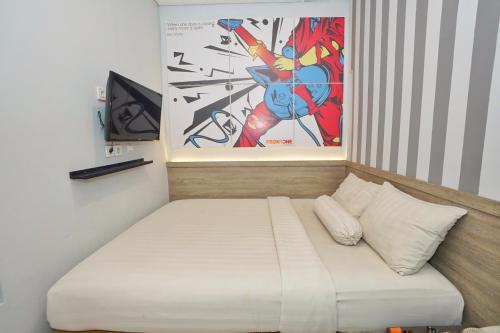 a bed in a room with a painting on the wall at Front One Cabin Setiabudi Solo in Solo