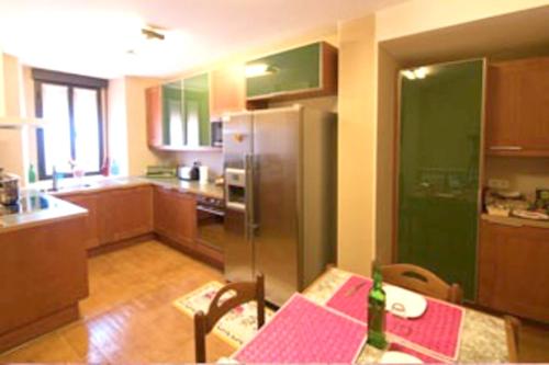 eine Küche mit einem Tisch und einem Kühlschrank aus Edelstahl in der Unterkunft 5 bedrooms house with terrace and wifi at Aldehuela Sepulveda in Hinojosas del Cerro