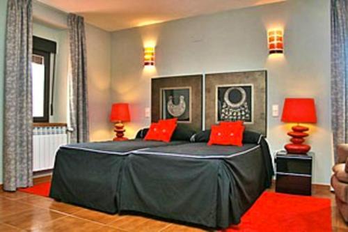una camera da letto con un grande letto nero con cuscini rossi di 5 bedrooms house with terrace and wifi at Aldehuela Sepulveda a Hinojosas del Cerro