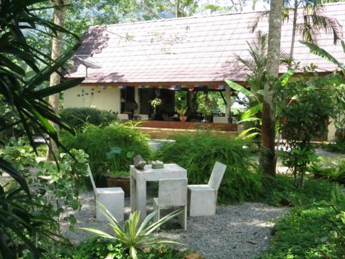 a garden with a table and chairs in front of a house at Manora Garden in Phangnga