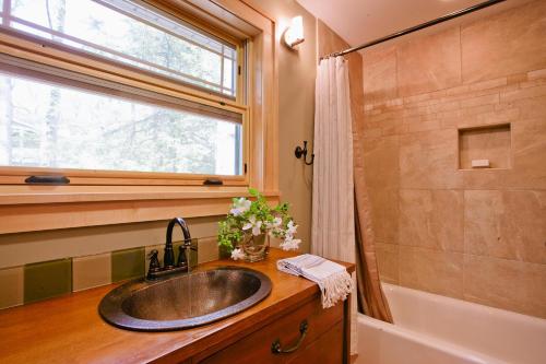 ein Badezimmer mit einem Waschbecken, einem Fenster und einer Badewanne in der Unterkunft Tulip Cottage in Black Mountain