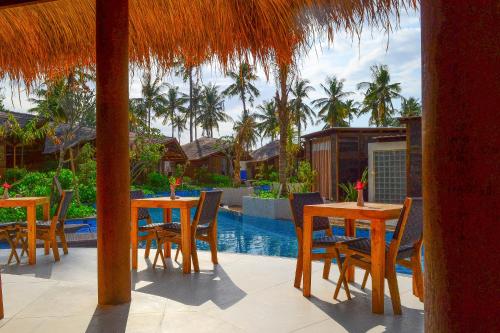 a patio area with chairs, tables and umbrellas at Gili Air Lagoon Resort in Gili Islands
