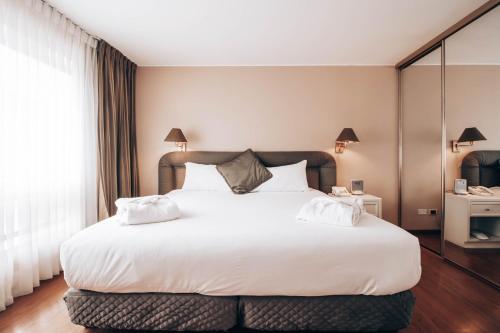 a bedroom with a large white bed with white pillows at Suites del Bosque Hotel in Lima