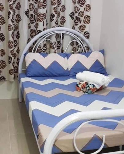 Bett mit blauer und weißer Bettwäsche und Kissen in der Unterkunft Melon Transient House in Angeles