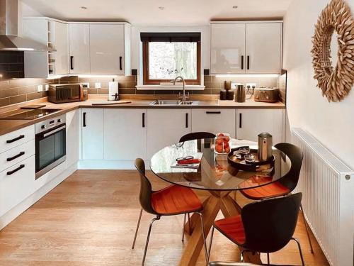 a kitchen with a glass table and chairs in it at Eco lodge with hot tub overlooking Cairngorms in Aviemore 