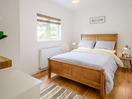 a bedroom with a wooden bed with white walls and a window at 1 bed property in Ilfracombe 56262 in Ilfracombe