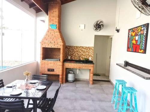 une salle à manger avec une table et une cheminée en briques dans l'établissement Island House : Sua Casa na Ilha!, à Ilha Comprida