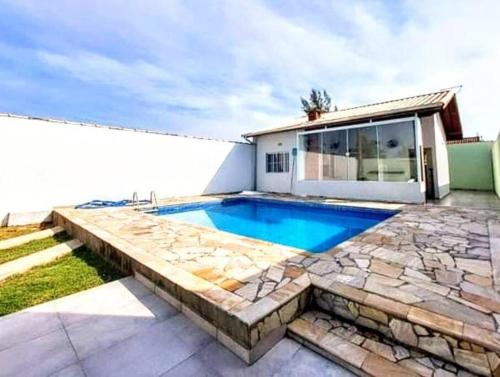 une cour arrière avec une piscine et un patio en pierre dans l'établissement Island House : Sua Casa na Ilha!, à Ilha Comprida