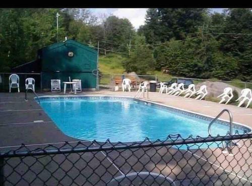 a swimming pool with white chairs and a fence at Lake Access with a View! Lake Wallenpaupack . in Greentown