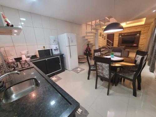 eine Küche und ein Esszimmer mit einem Tisch und einem Kühlschrank in der Unterkunft Lindo sobrado a beira rio in Piçarras