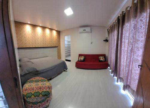 ein Schlafzimmer mit einem Bett und einem roten Stuhl in der Unterkunft Lindo sobrado a beira rio in Piçarras