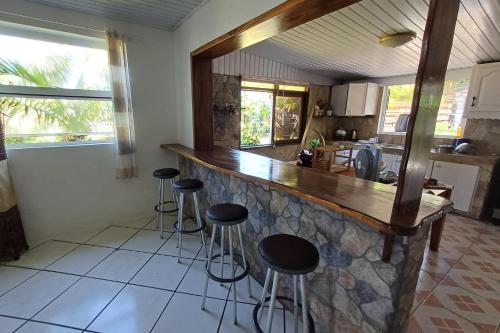 una cucina con bancone e sgabelli in una stanza di Faré Ahonu beach house a Mahina