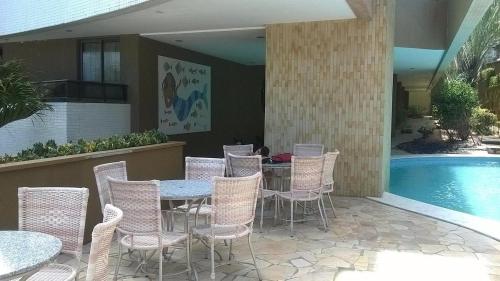 a patio with tables and chairs next to a swimming pool at Mirador Vista Mar 110 in Natal