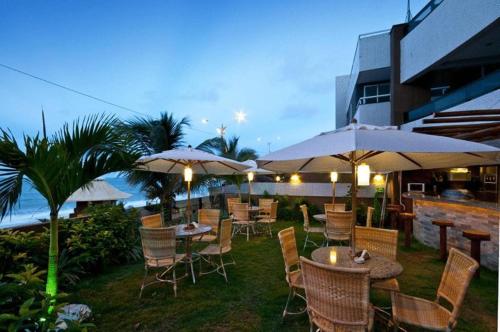 an outdoor restaurant with tables and chairs and umbrellas at Mirador Vista Mar 110 in Natal