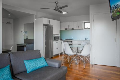 a living room with a couch and a kitchen at Essence Apartments Chermside in Brisbane