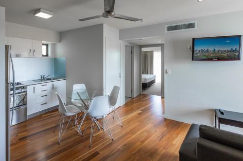 a kitchen and a living room with a table and chairs at Essence Apartments Chermside in Brisbane