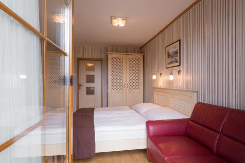 a bedroom with a bed and a red couch at Hotel Maxant in Frymburk