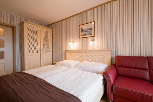 a bedroom with a bed and a red chair at Hotel Maxant in Frymburk
