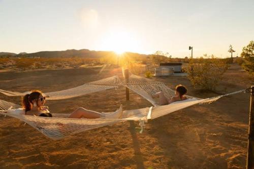 LandersにあるDagger Tree Oasis l Integratron 5Bed and Cowboy Poolの浜辺のハンモックに寝転がる二人