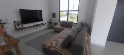 a living room with a couch and a flat screen tv at Casa de campo 1h30 de SP Ninho verde 1 in Porangaba