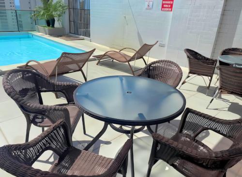 a glass table and chairs in front of a pool at FLAT Boa Viagem - 50m da Praia - Garagem GRÁTIS - 24H CHECK IN - in Recife