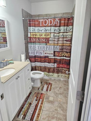 a bathroom with a toilet and a shower curtain at Charming Oasis in Worthville