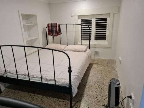 a bedroom with a black bed with a window at Cosy Studio Walk to Bondi and Bronte Beaches in Sydney