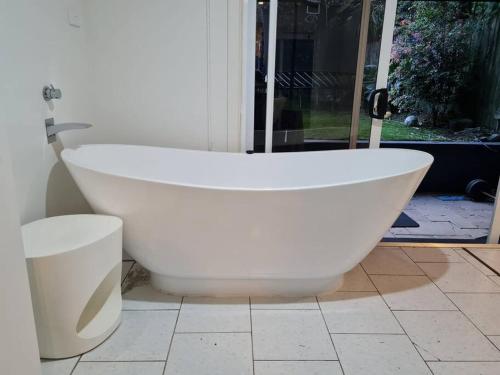 a white bath tub sitting on a tile floor at Cosy Studio Walk to Bondi and Bronte Beaches in Sydney