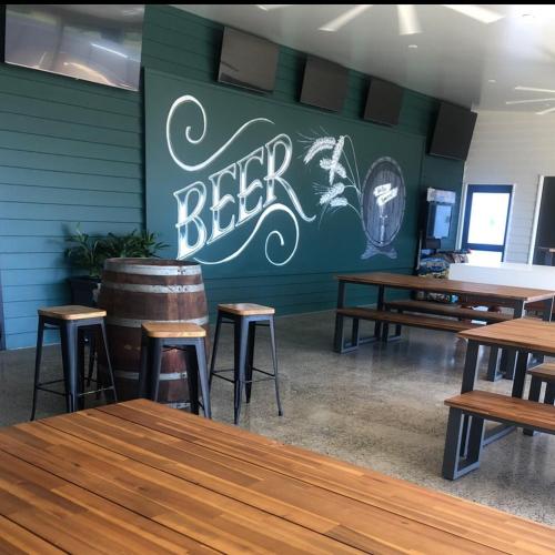 un ristorante con tavoli in legno e un cartello con la birra sul muro di Pally Pub 
