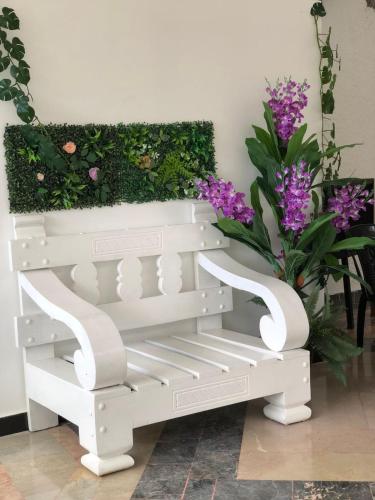 a white bench in front of a garden with purple flowers at Garden Hotel in Cuevas