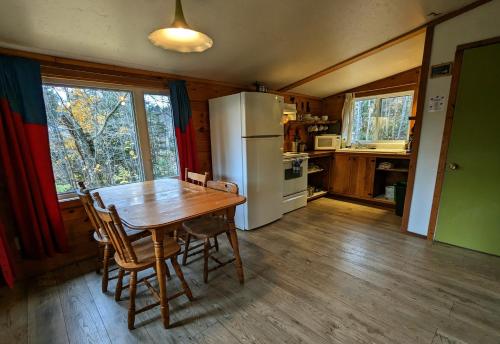 a kitchen with a wooden table and a refrigerator at Chalets Aux Berges du Lac Castor in Saint-Paulin