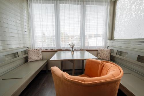 a dining room with an orange chair and a table at Hotel Maxant in Frymburk