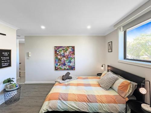 a bedroom with a bed and a painting on the wall at Funky Fitzroy apartment so close to the action in Melbourne
