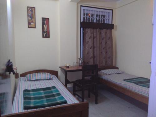 a small room with two beds and a desk at Hotel Prince B in Guwahati