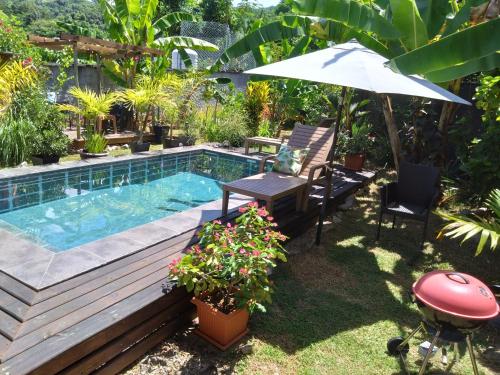 un patio trasero con piscina, mesa y sombrilla en A Peace In Paradise, en Baie Lazare Mahé