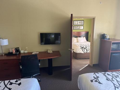a room with a desk and a bedroom with a bed at Sleep Inn & Suites at Six Flags in San Antonio