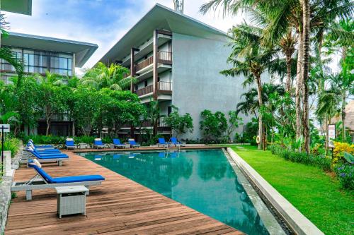 a resort swimming pool with lounge chairs and a building at Wyndham Tamansari Jivva Resort Bali in Keramas