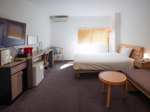 鹿児島市にあるYou Style Hotel MARINEのベッド、デスク、テレビが備わるホテルルームです。