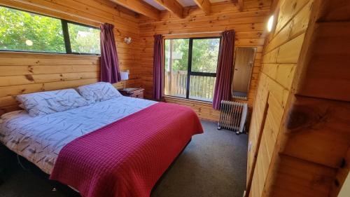 a bedroom with a bed in a wooden cabin at 19 Torquay Terrace in Hanmer Springs