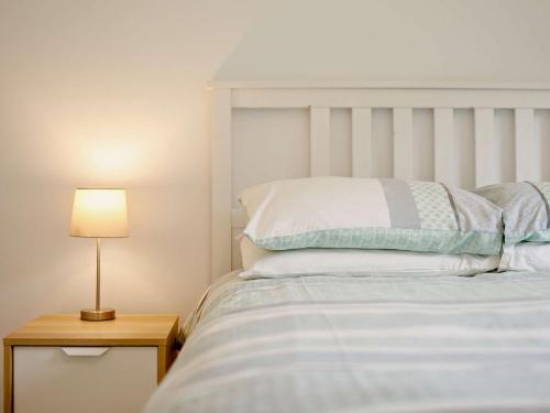 uma cama com uma cabeceira branca e uma mesa com um candeeiro em 2 Bed in Whitsand Bay 88309 em Landrake