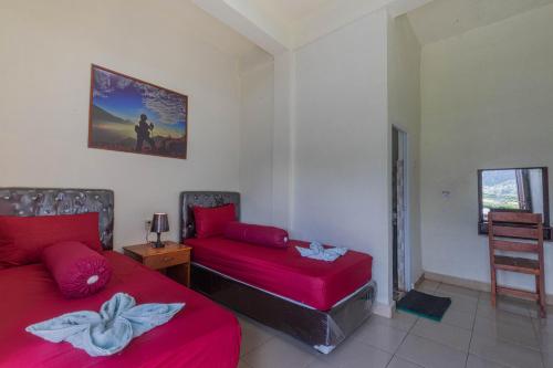 a bedroom with two beds and a table and a chair at Teras Sawah Guest House Syariah in Sembalun Lawang