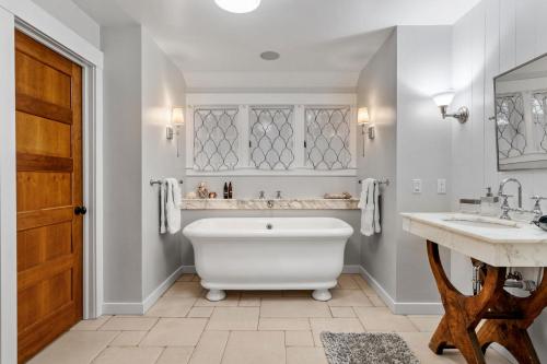 ein Badezimmer mit einer weißen Badewanne, 2 Waschbecken und einer Holztür in der Unterkunft Design House at Linden Hills in Minneapolis