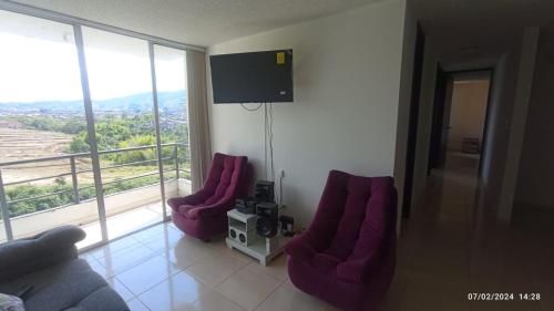 sala de estar con 2 sillas de color púrpura y TV en Santa Rosa De Cabal - Acogedor apartamento, en Santa Rosa de Cabal