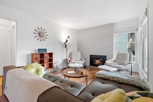 een woonkamer met een bank en stoelen en een open haard bij Hygge House in Minneapolis