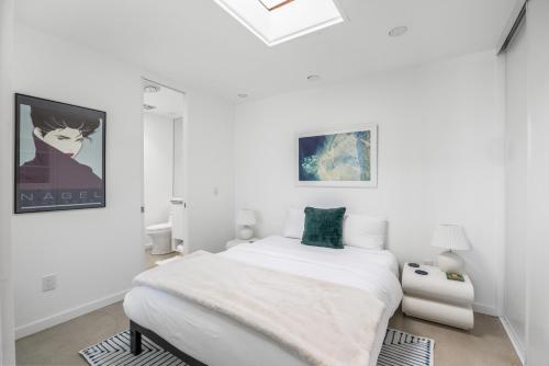 a white bedroom with a bed and a painting on the wall at Private Pool & Mountain Views! in Palm Springs