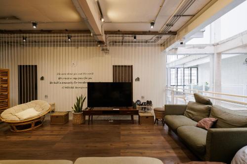 a living room with a couch and a flat screen tv at C'HOUSE Bangkok in Pom Prap