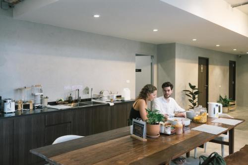 a man and woman sitting at a table in a kitchen at C'HOUSE Bangkok in Pom Prap