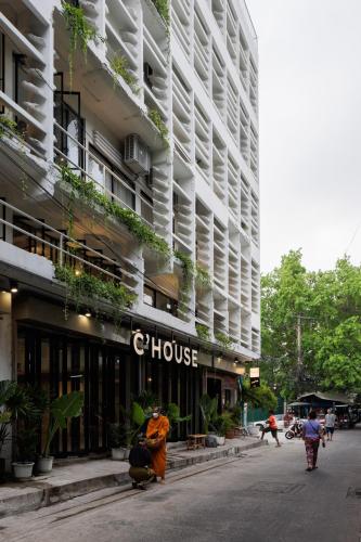 a building with a woman standing in front of it at C'HOUSE Bangkok in Pom Prap